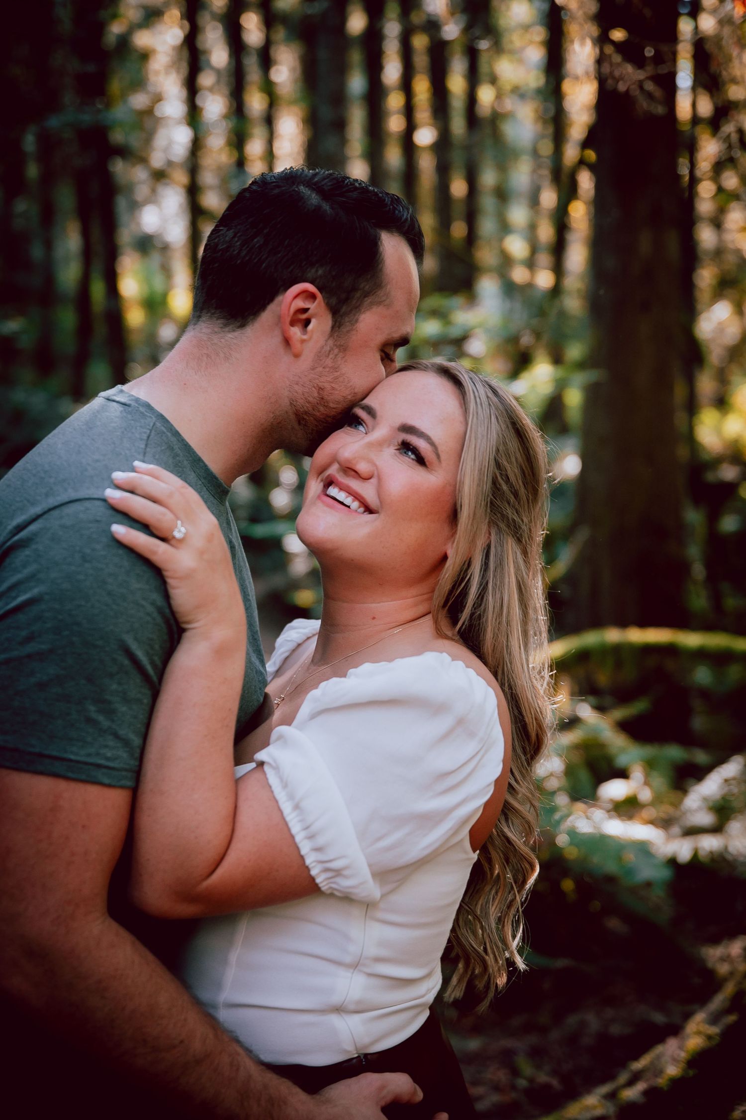 Romantic couple sharing intimate moment in sunlit forest.