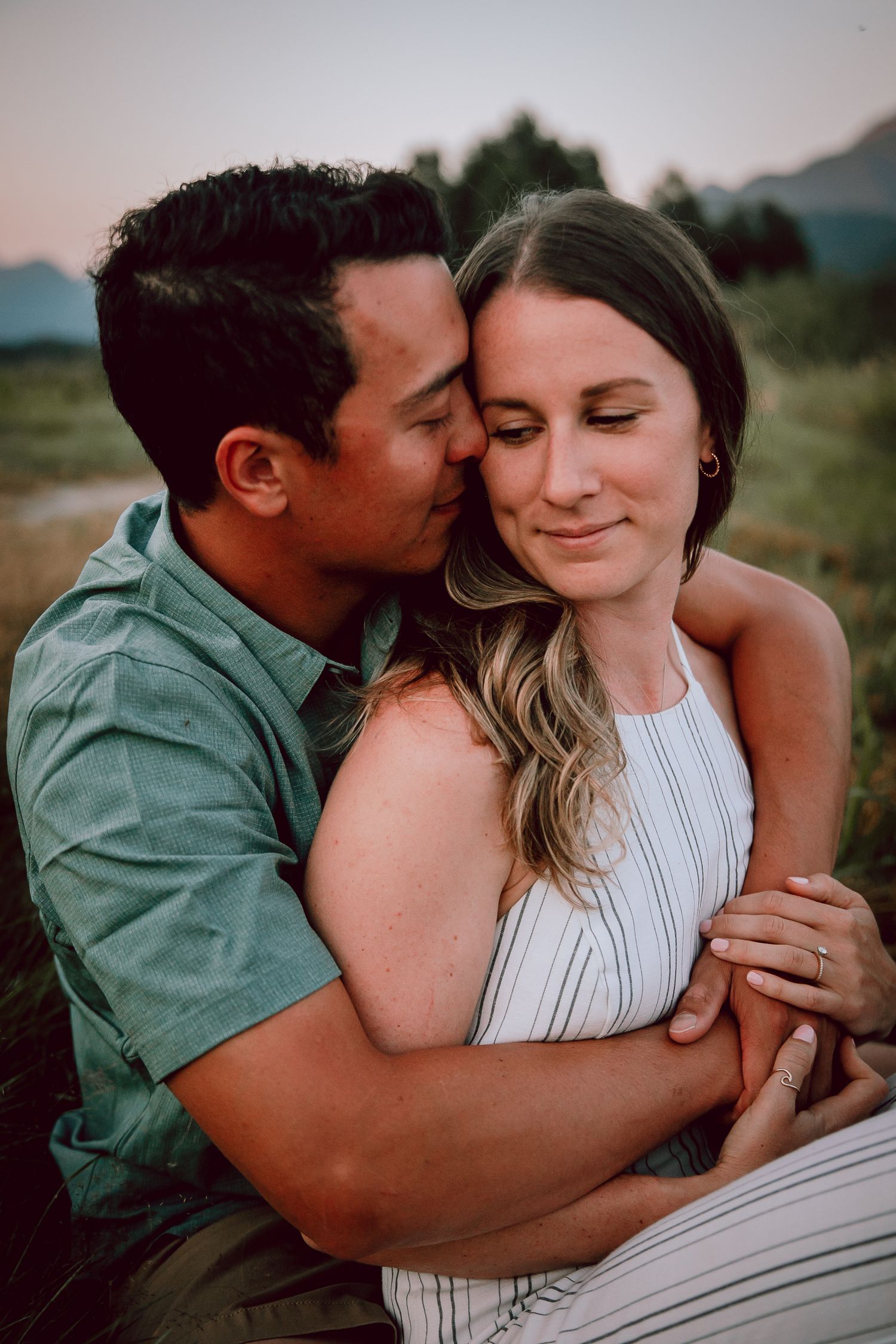 A tender romantic moment captured between a couple in an outdoor mountain setting.