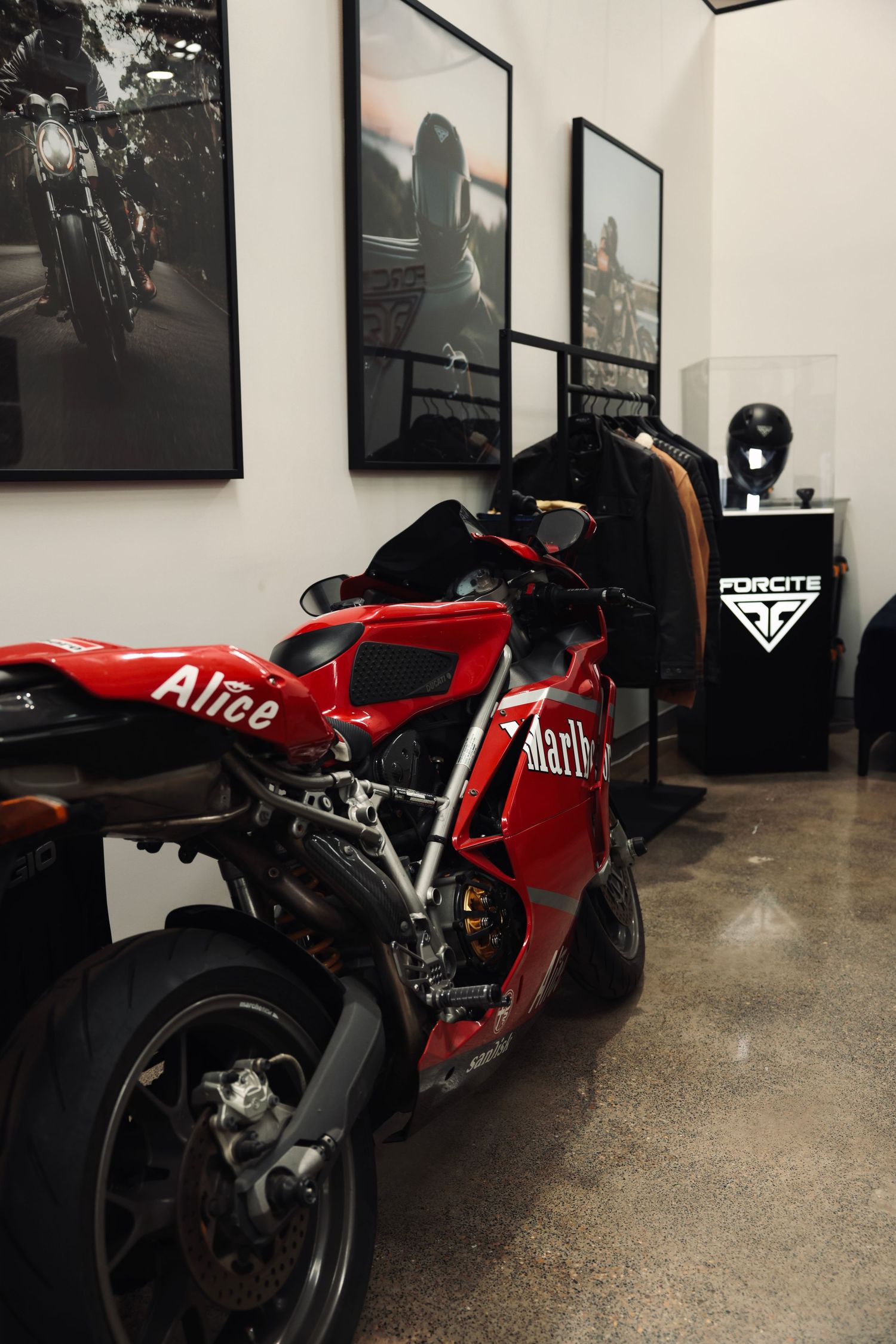 Red motorcycles on display in a showroom with black and white photography on walls.