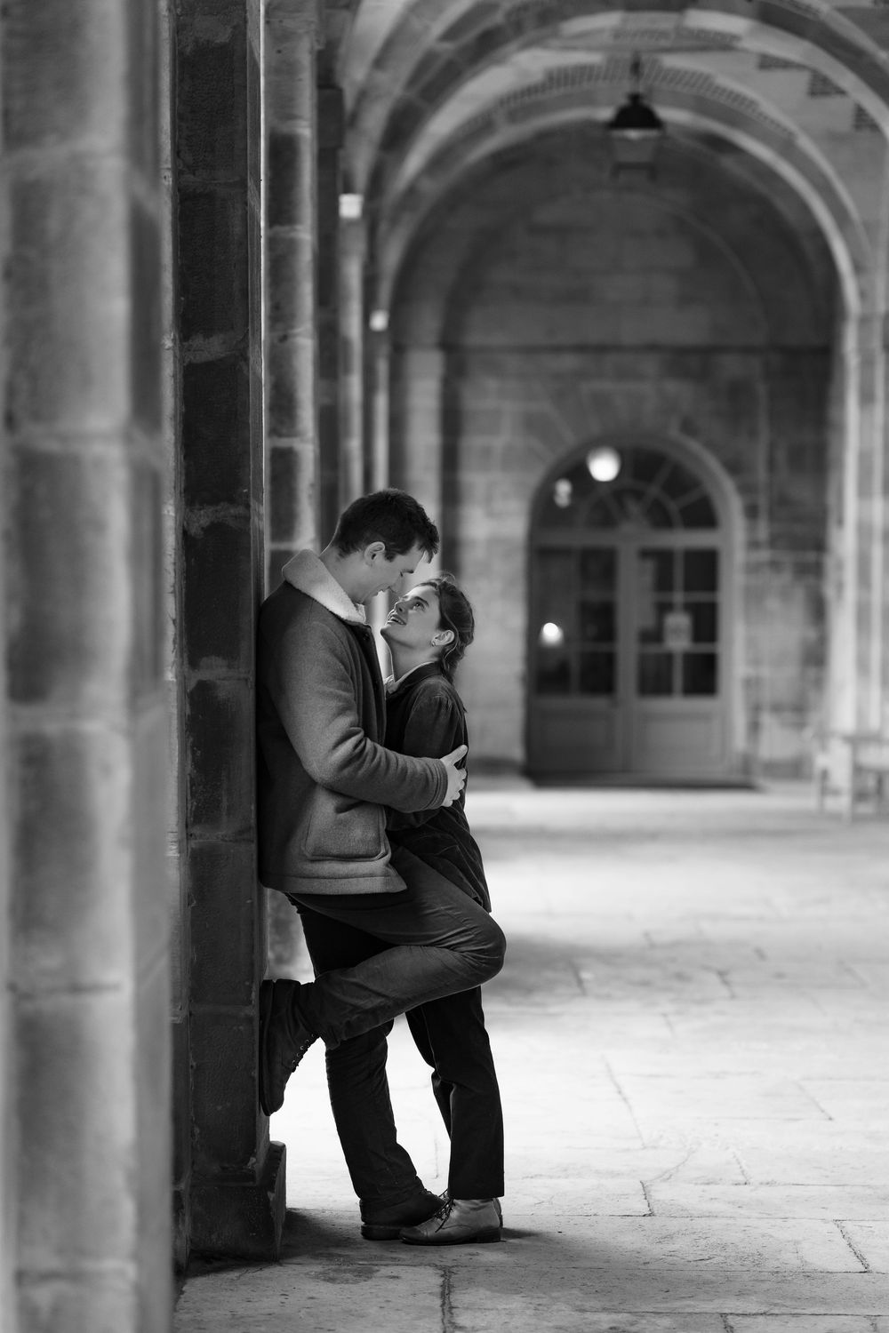Photo en noir et blanc d'un couple d'amoureux sous des arcades