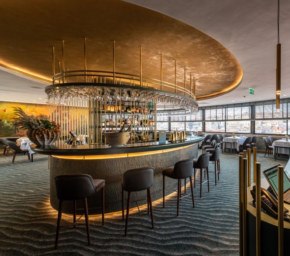 Luxurious curved bar with velvet stools and golden ceiling in an upscale lounge featuring modern lighting fixtures.