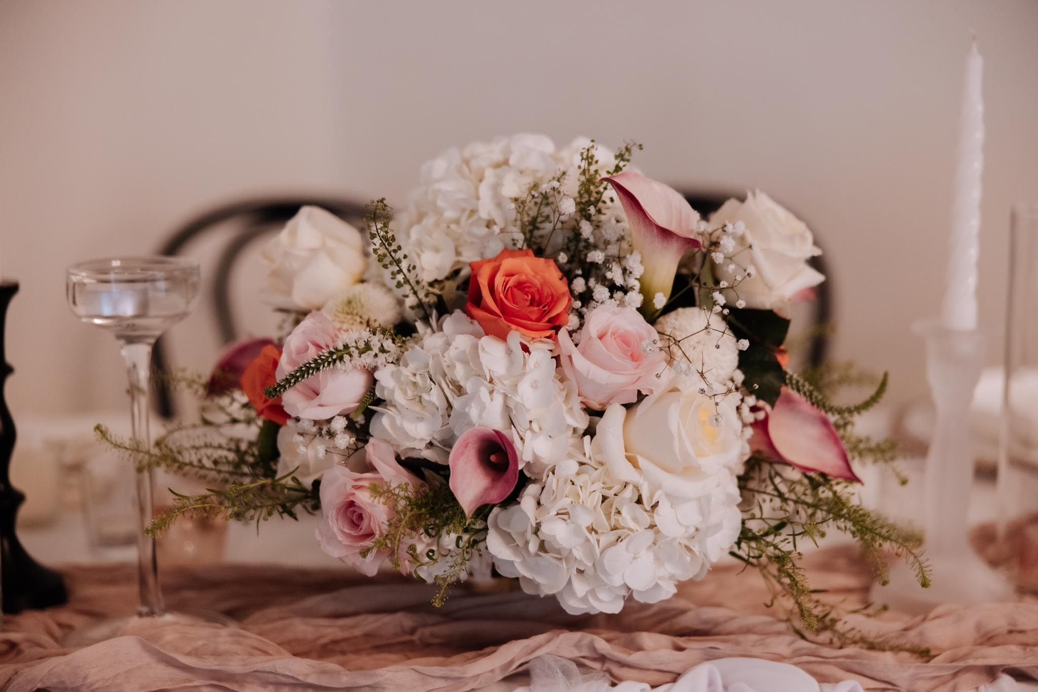 A romantic floral centerpiece with pink roses, white hydrangeas and delicate greenery on a wedding table.