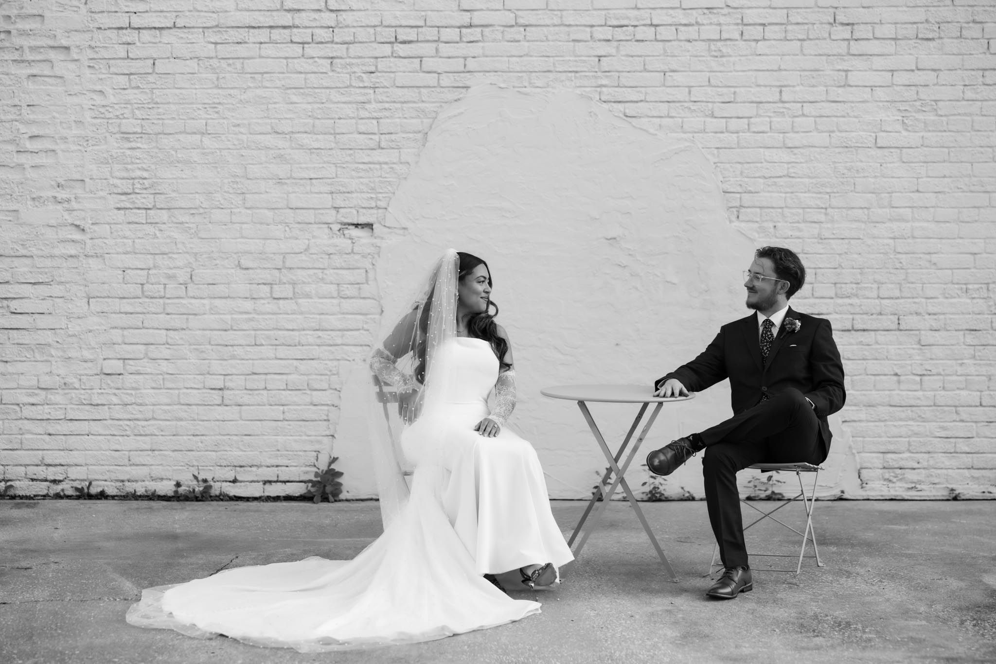 A black and white wedding photo series showing couples posing against a brick wall in artistic compositions.