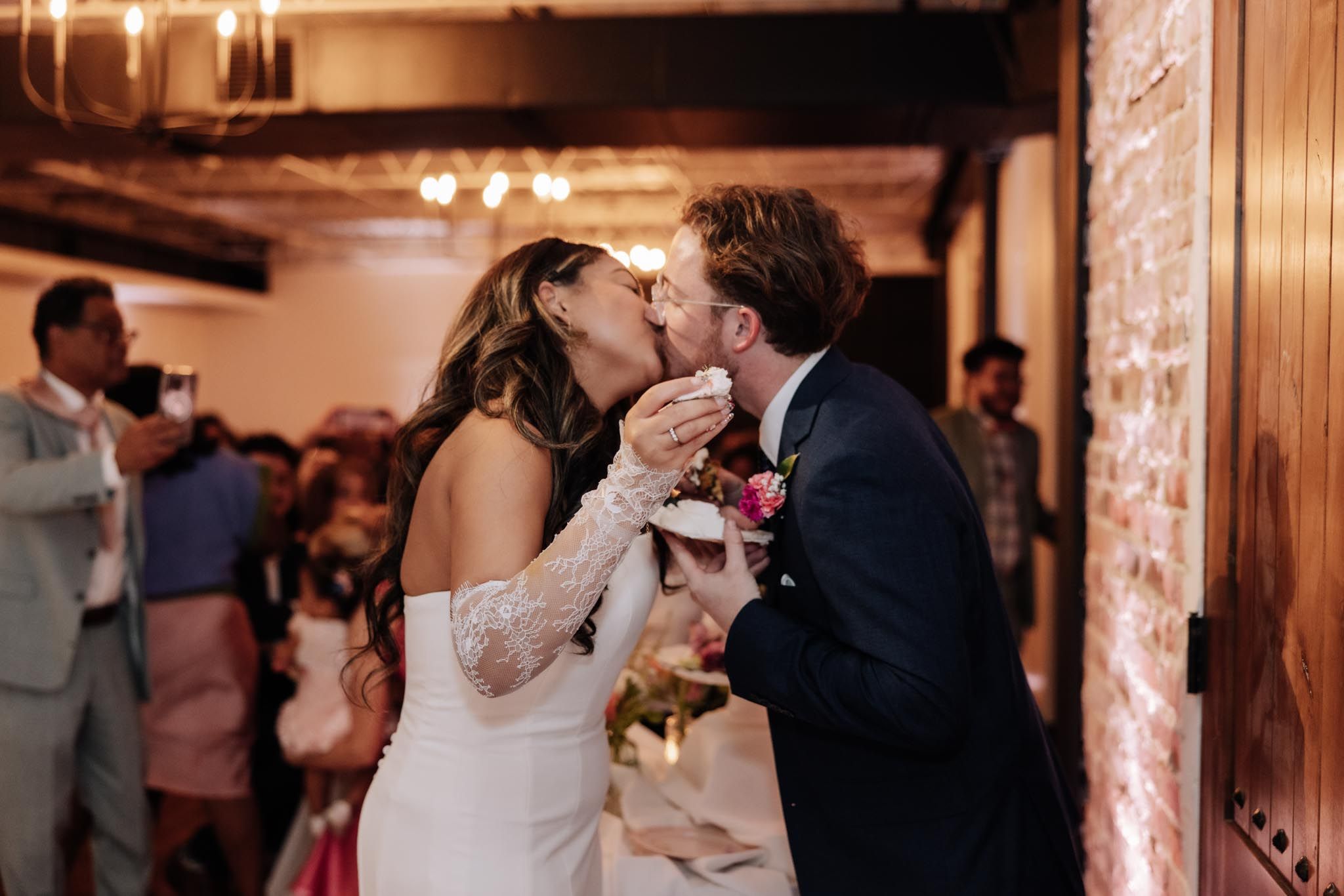 Couple sharing a romantic kiss during their wedding reception in an elegantly lit ballroom.