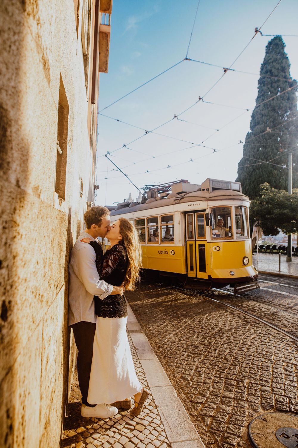 A romantic photo sequence showing a couple embracing near iconic yellow trams on Lisbon's historic cobblestone streets.