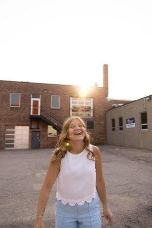 Sioux City, Iowa photographer. Smiling blonde woman  standing outdoors with golden sunset behind brick building.