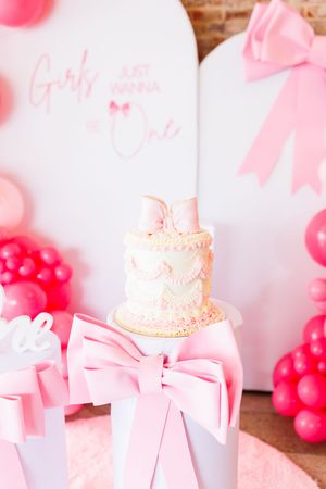 Pink and white party decorations with balloons and gift boxes create a feminine celebration setting.
