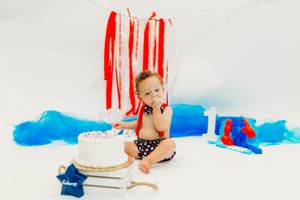 Red and blue decorations create a patriotic backdrop for a first birthday celebration setup.