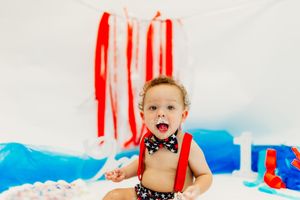 A patriotic themed birthday setup featuring red streamers, blue decorations and a white cake on display.