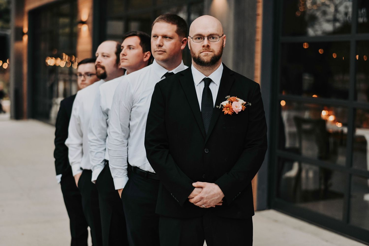the groom stares into the camera as his groomsmen candidly look away
