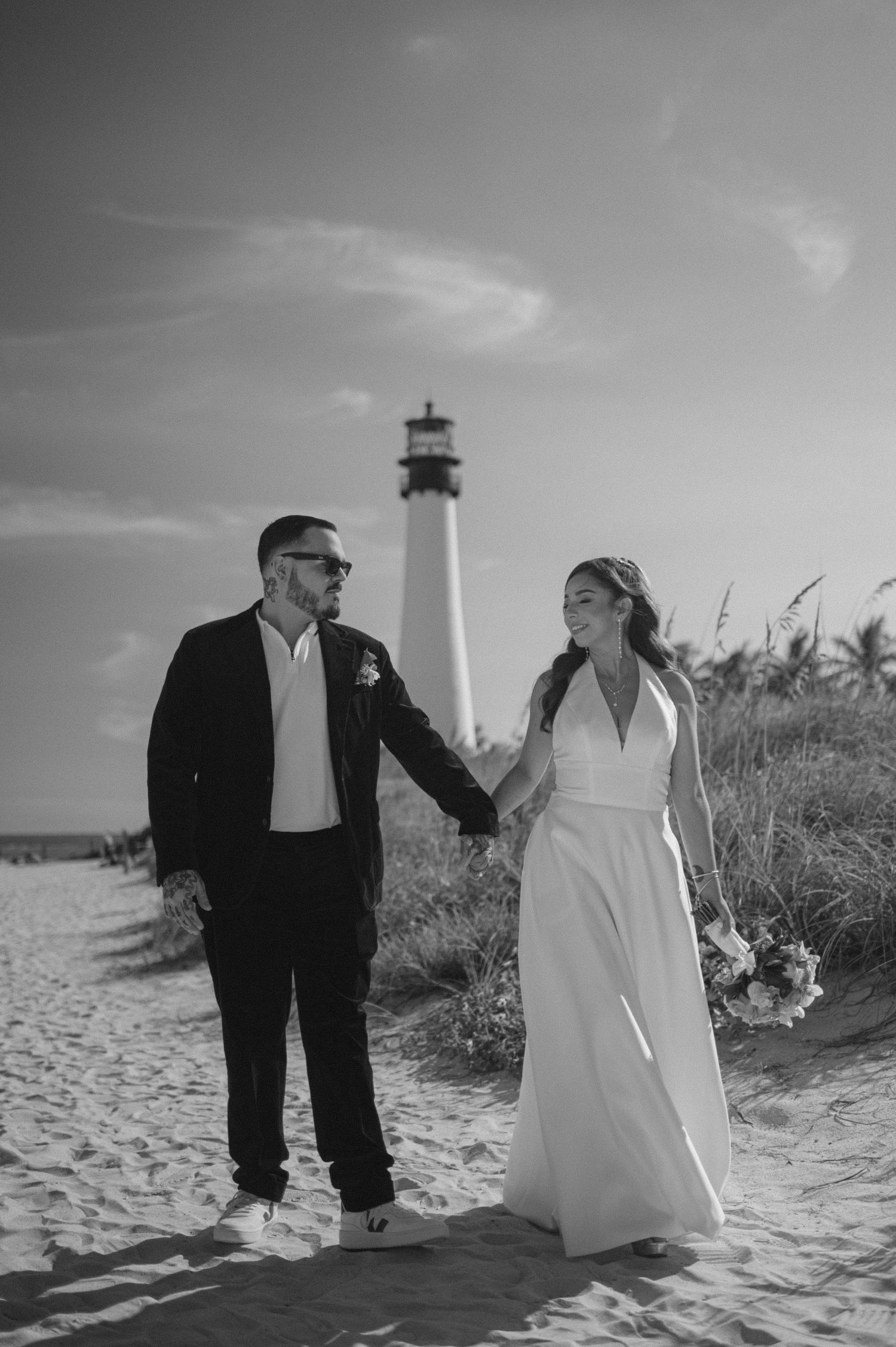 A romantic black and white photo series showing a couple walking together on a sandy beach.