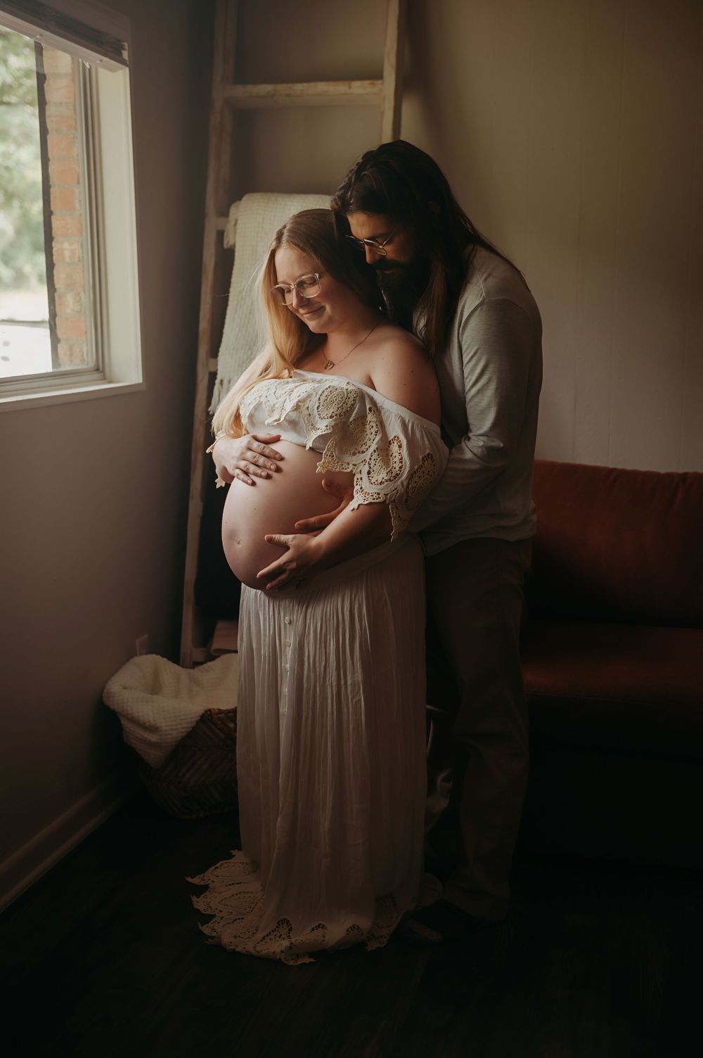 Intimate maternity photo series in natural window light showing tender moments between expectant parents.