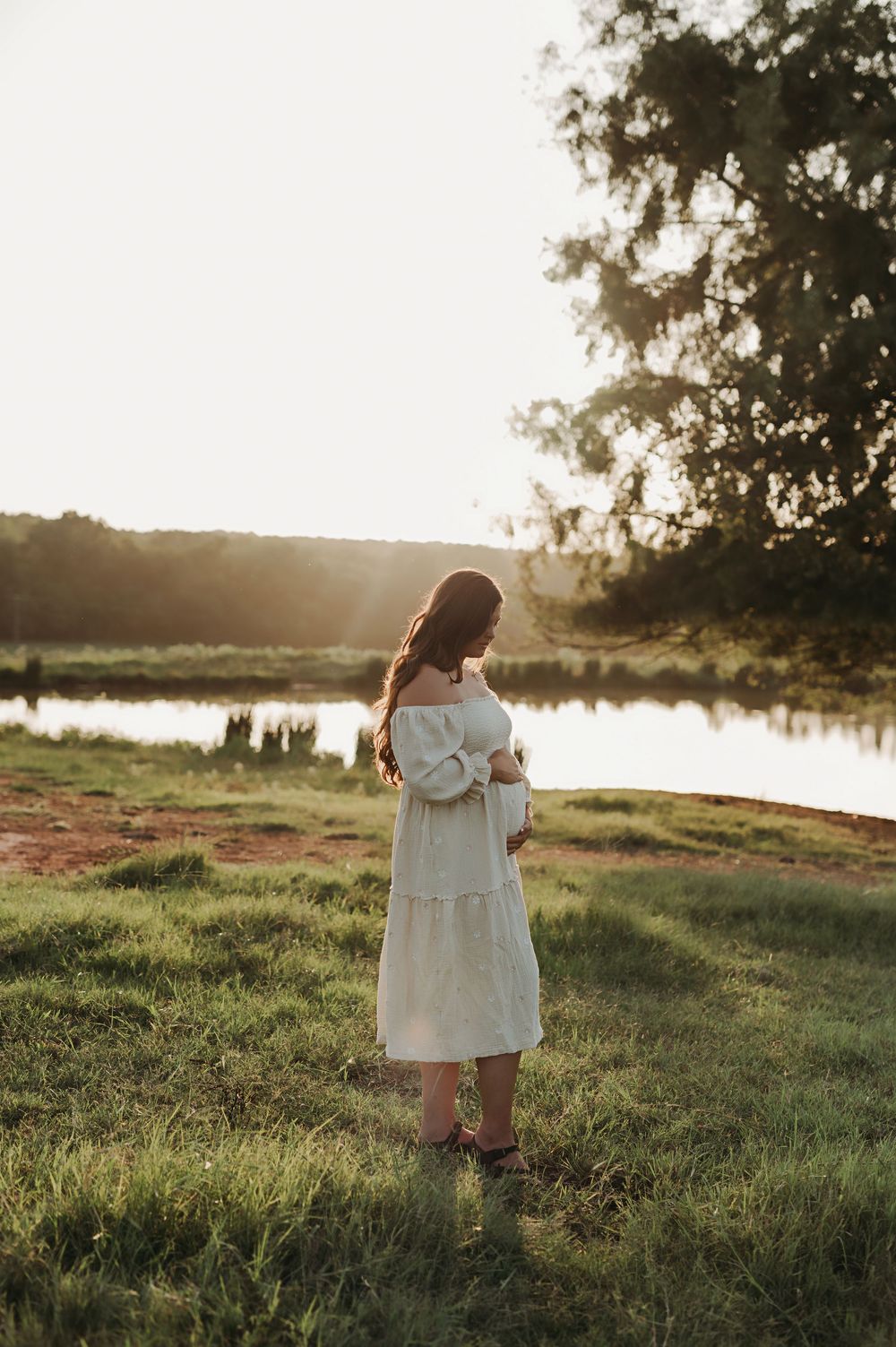 Pregnant mom in a field at sunset.