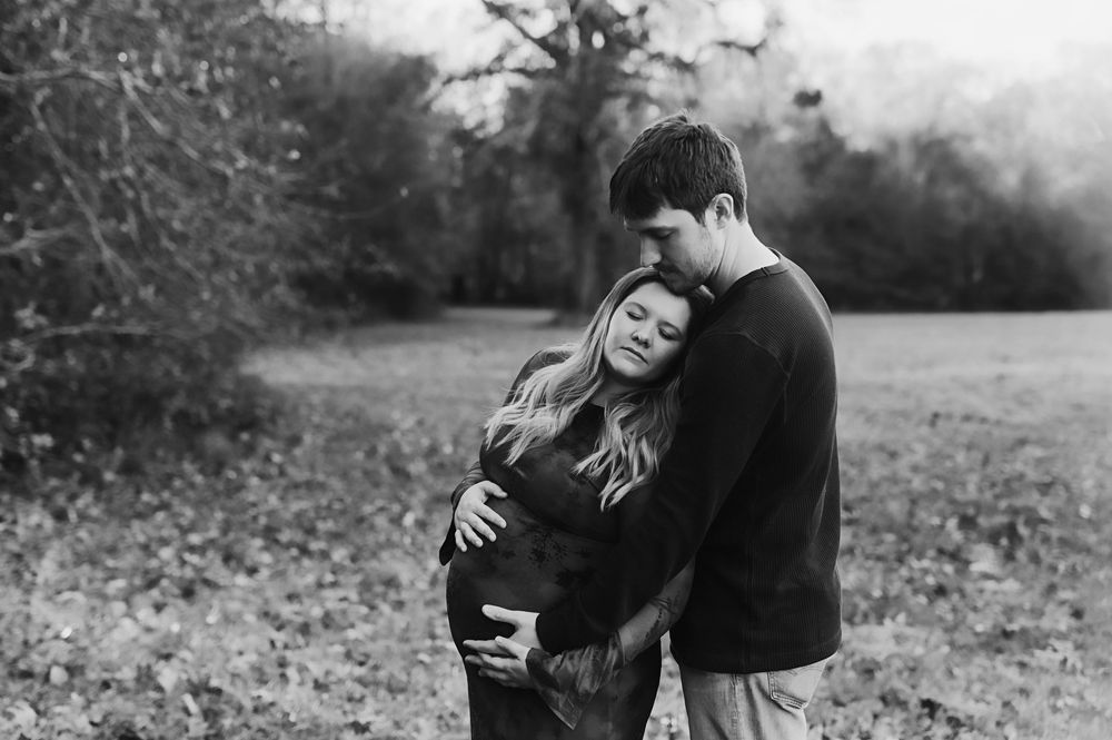 A romantic black and white photo series shows a couple embracing and sharing intimate moments in a natural outdoor setting.