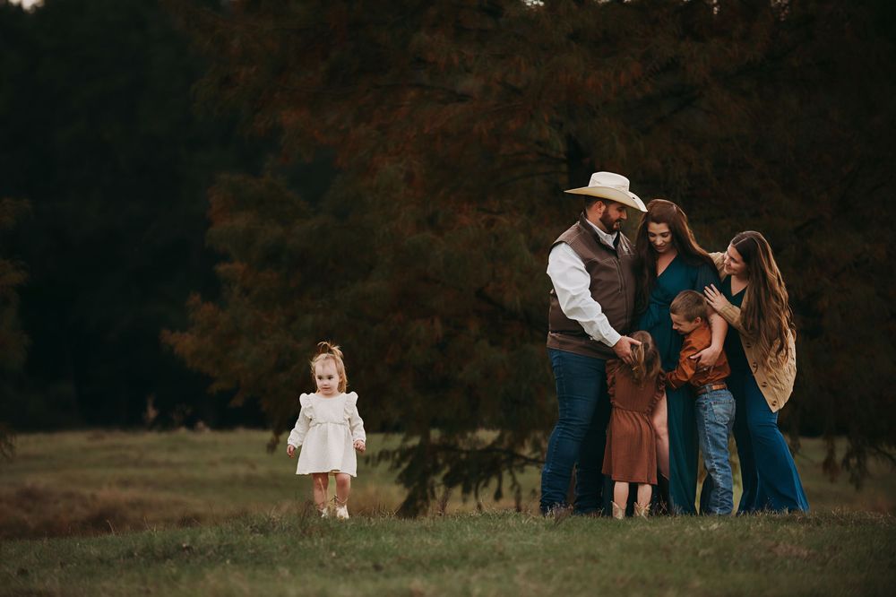 A group of people gather in a park during autumn with warm lighting and fall foliage in the background.