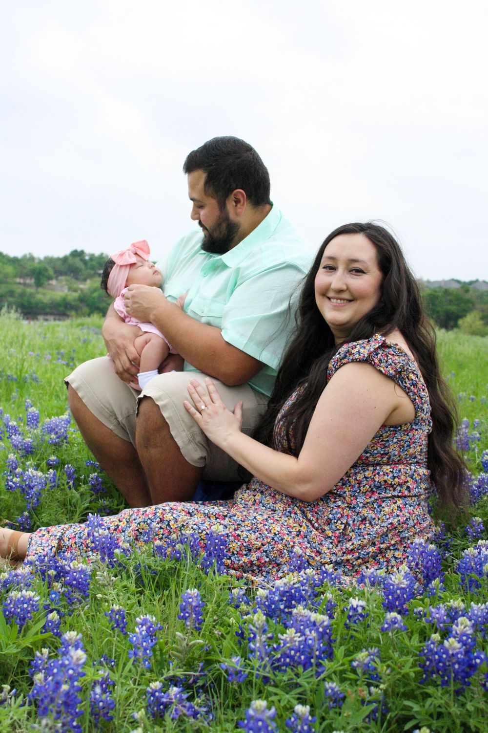 A couple sits together in a field of blooming Texas bluebonnets on a spring day.