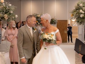 A couple shares a tender moment during their wedding ceremony while guests look on in a beautifully decorated venue.