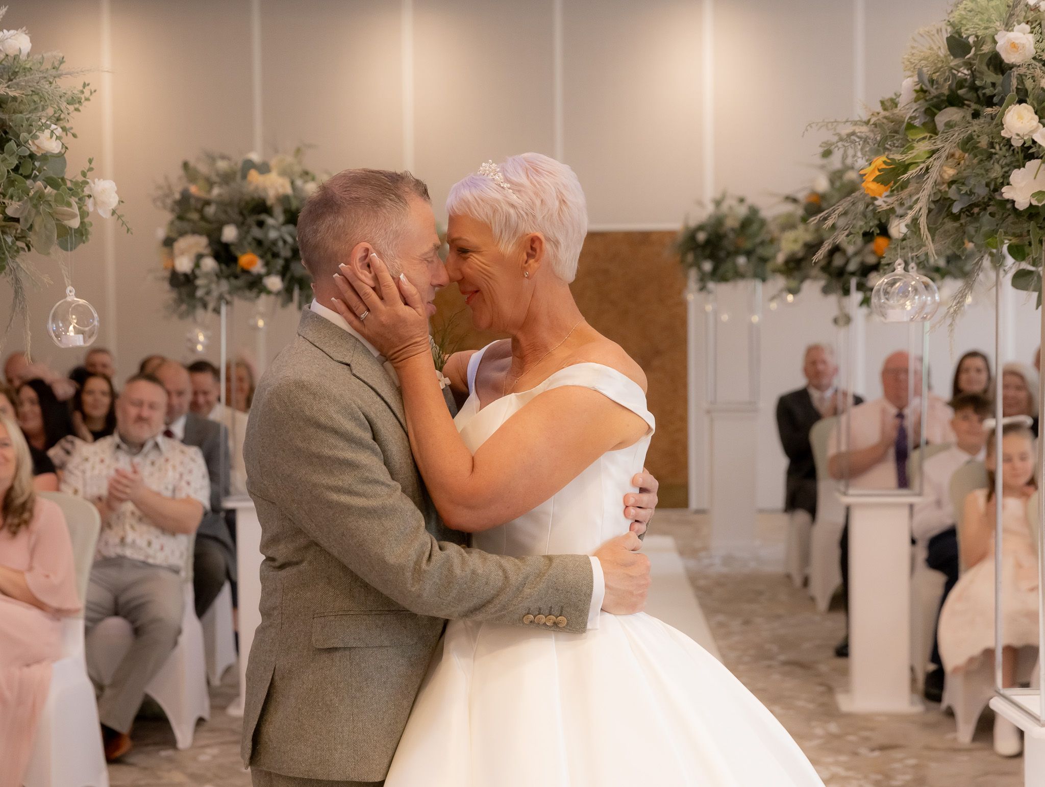 Elegant wedding celebration in a beautifully decorated indoor venue with white floral arrangements and romantic lighting.