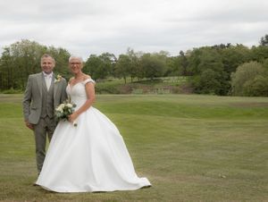 Newlyweds share intimate moments on a scenic golf course with rolling green hills in the background.