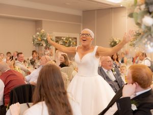 Wedding reception guests dancing and celebrating together in a bright indoor venue.