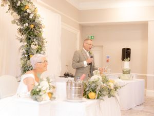 Wedding reception venue decorated in white with elegant floral arrangements and modern minimalist design.