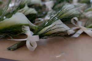 Close-up of elegant greenery and white floral decorations arranged on a table surface.