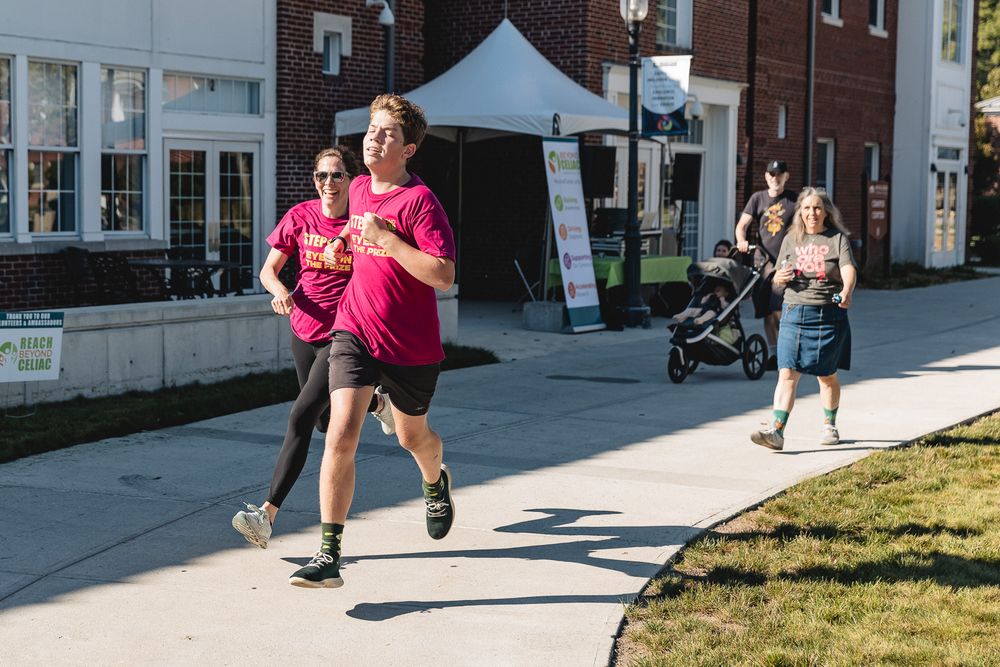 People participating in a community running event on a sidewalk near brick buildings.