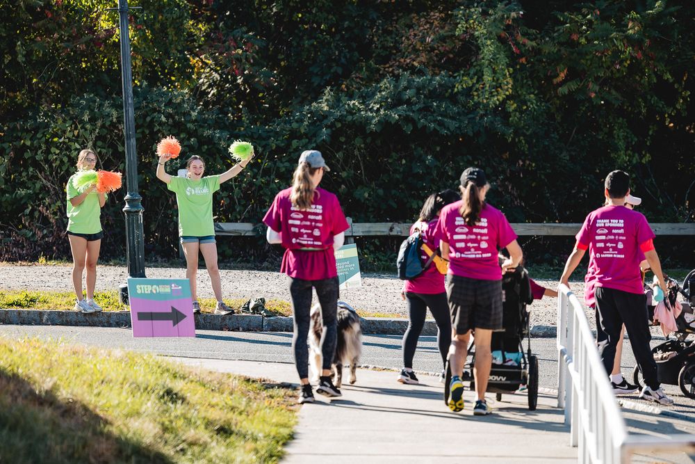 A group of people walking along a paved path during an outdoor community event.