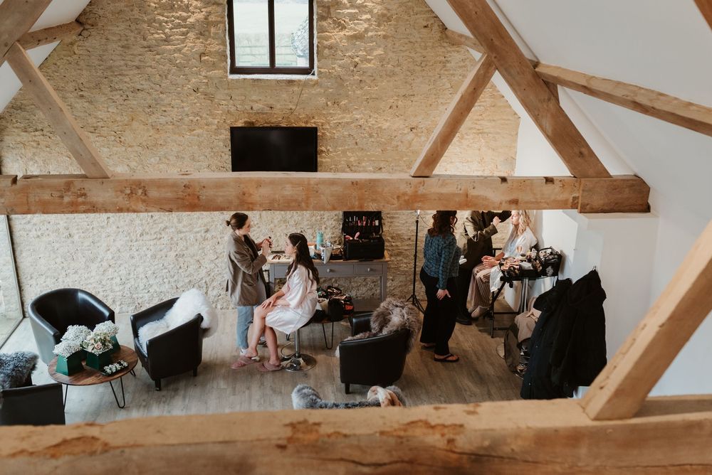 A rustic barn venue with exposed wooden beams and natural light streaming through large windows during a wedding reception.
