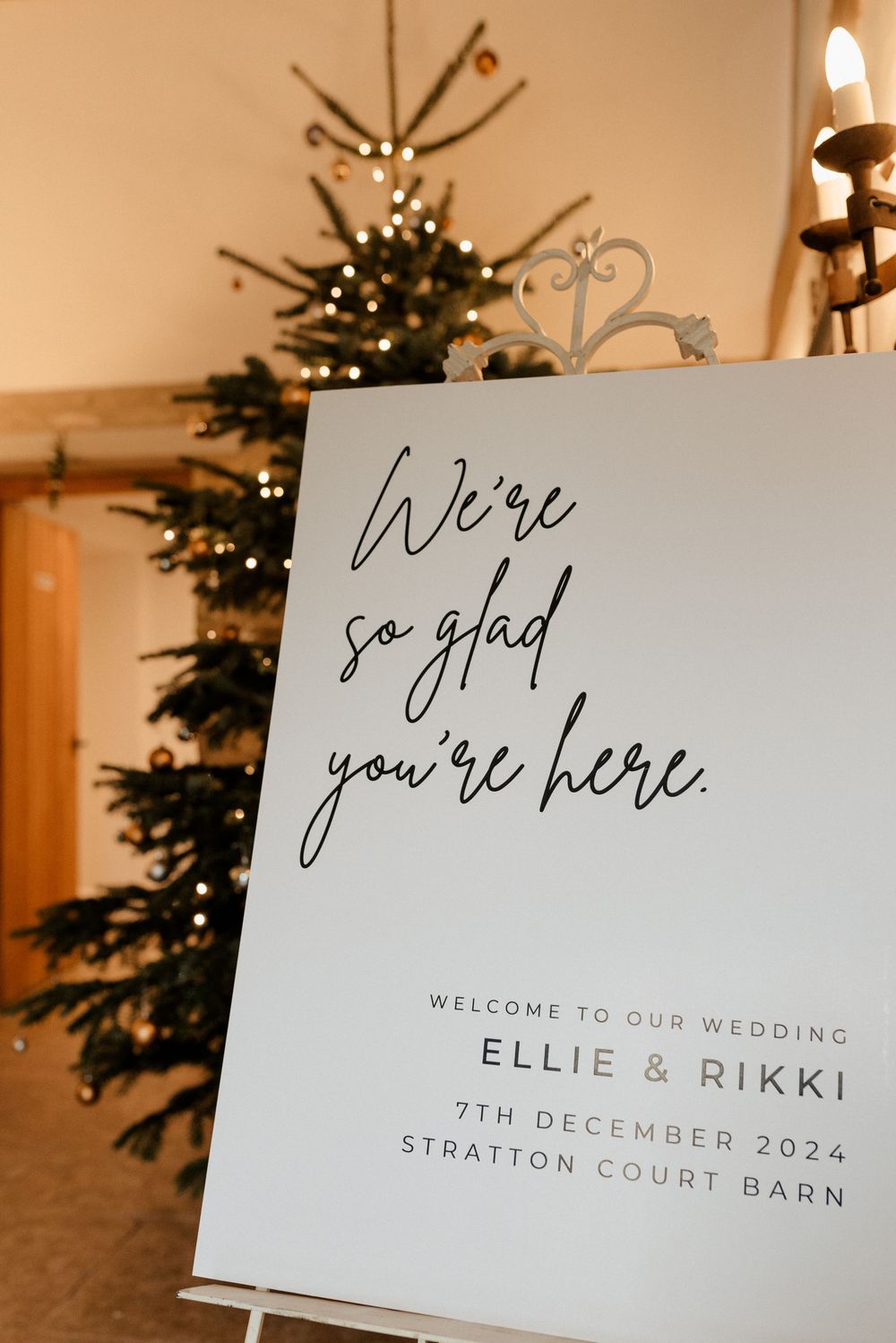 Elegant wedding welcome sign with calligraphy text 'We're so glad you're here' displayed at Court Barn venue.