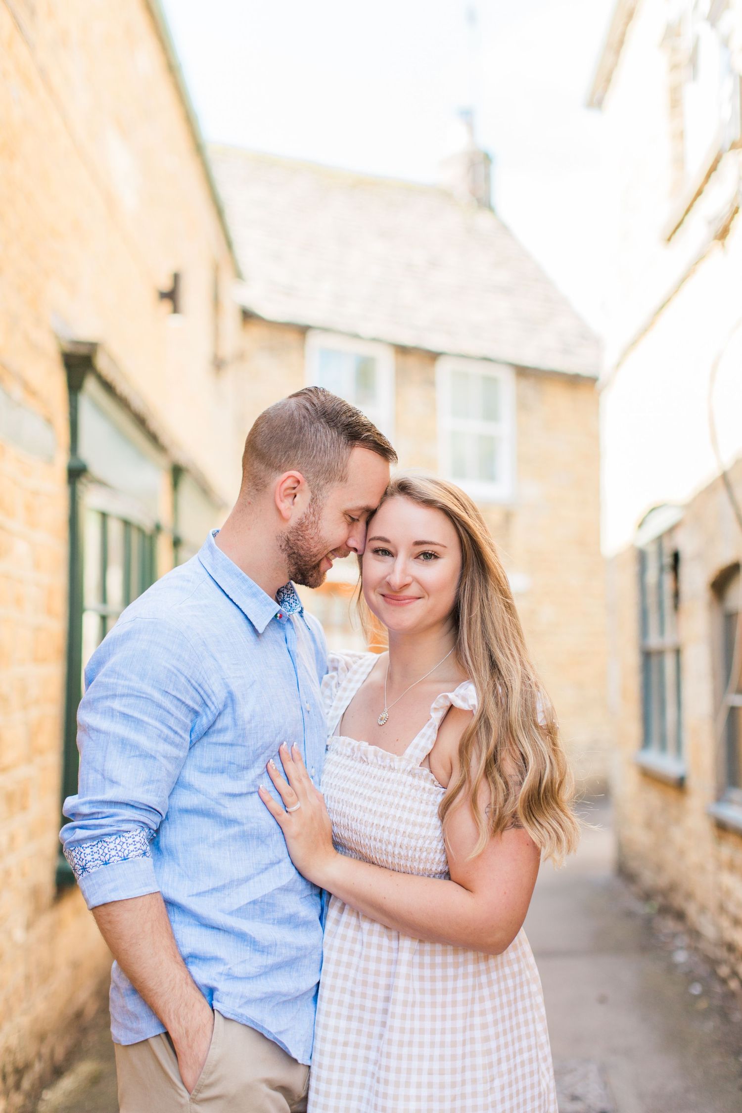 A newly engaged couple shares an intimate moment together while walking in Bourton on the Water Cotswolds. Hayley Elizabeth photography