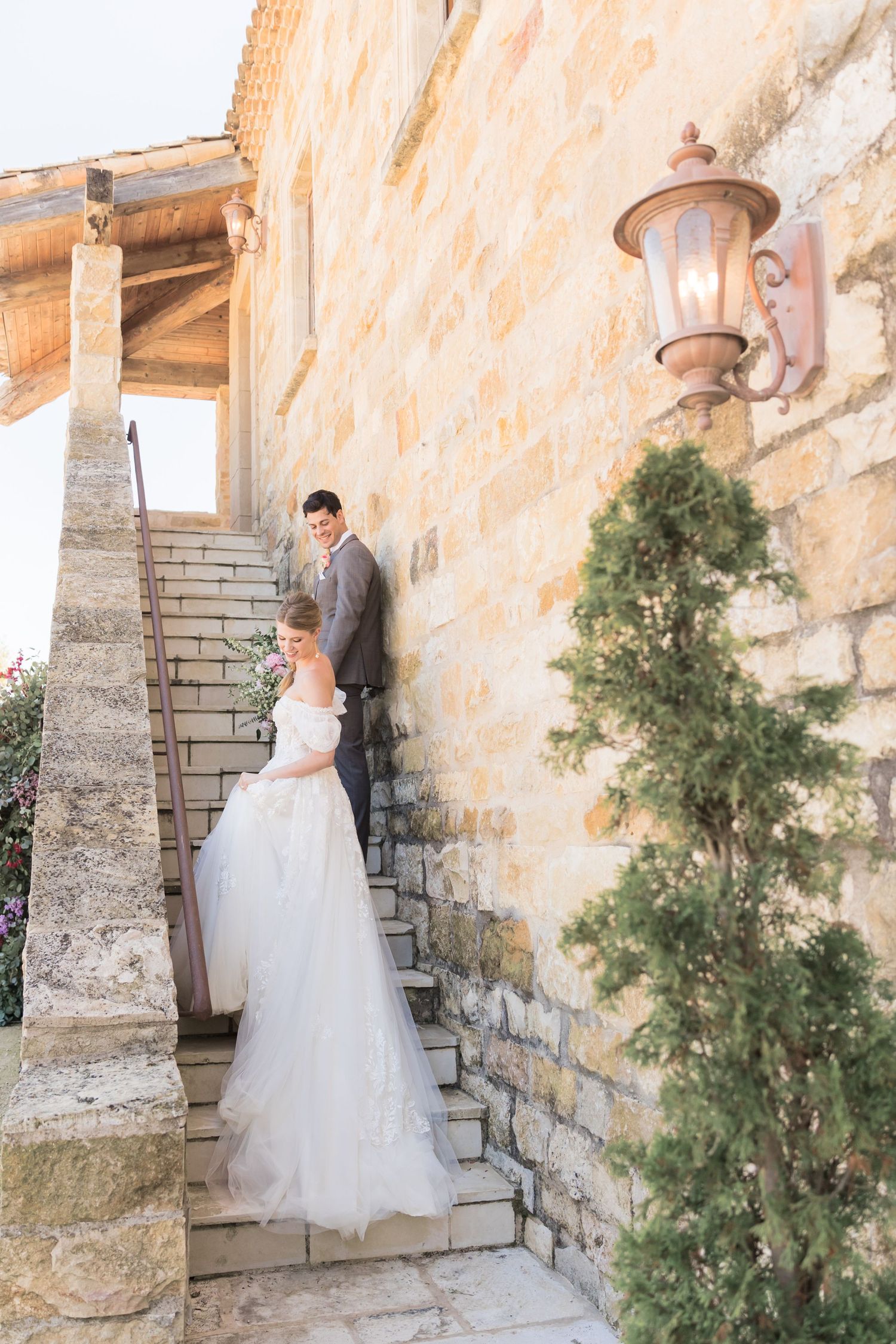Romantic wedding couple shares intimate moments among delicate purple wildflowers in a sunlit rustic setting.