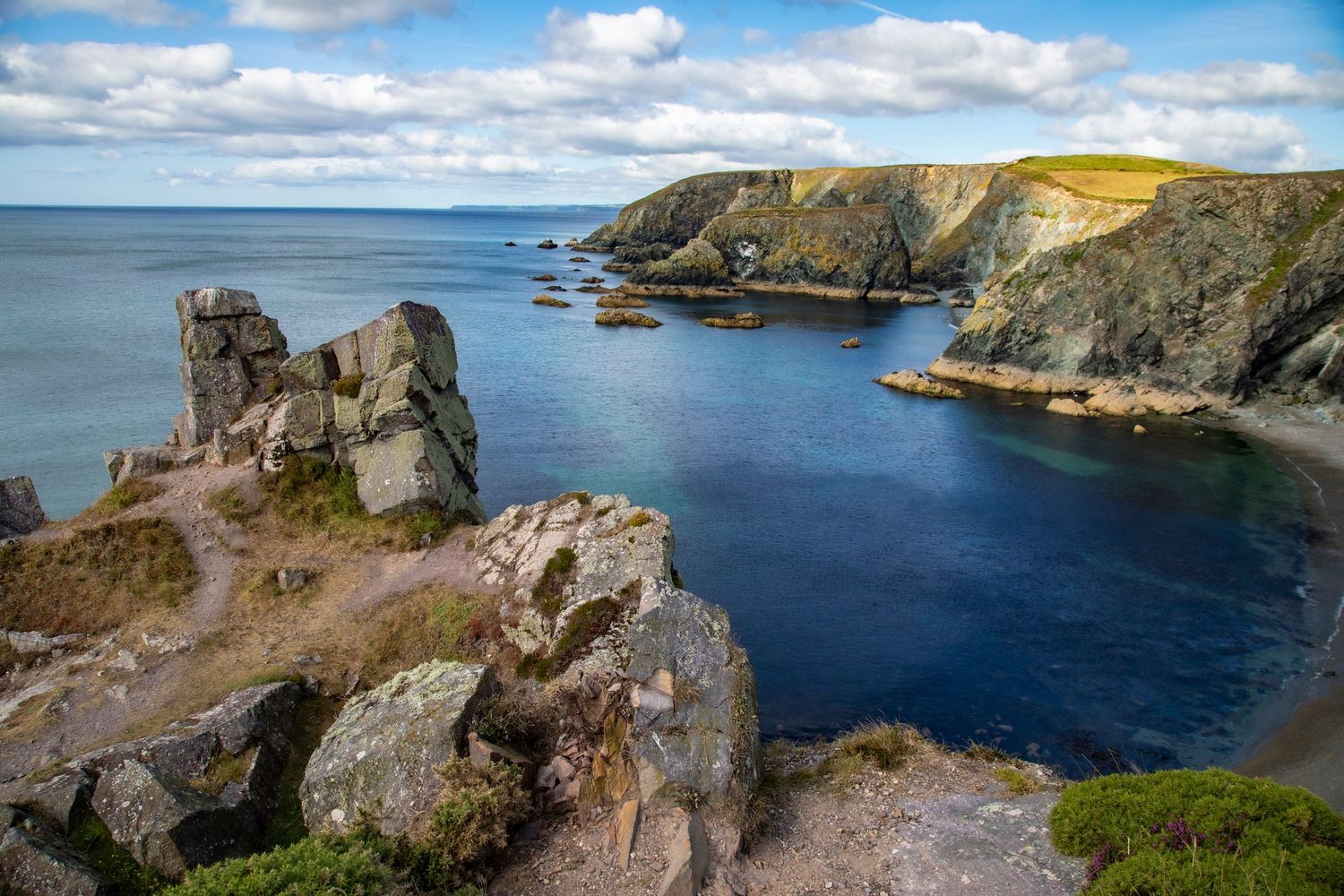 Dramatic coastal landscape of Ireland showing rugged cliffs and turquoise waters along the scenic coastline on a sunny day.