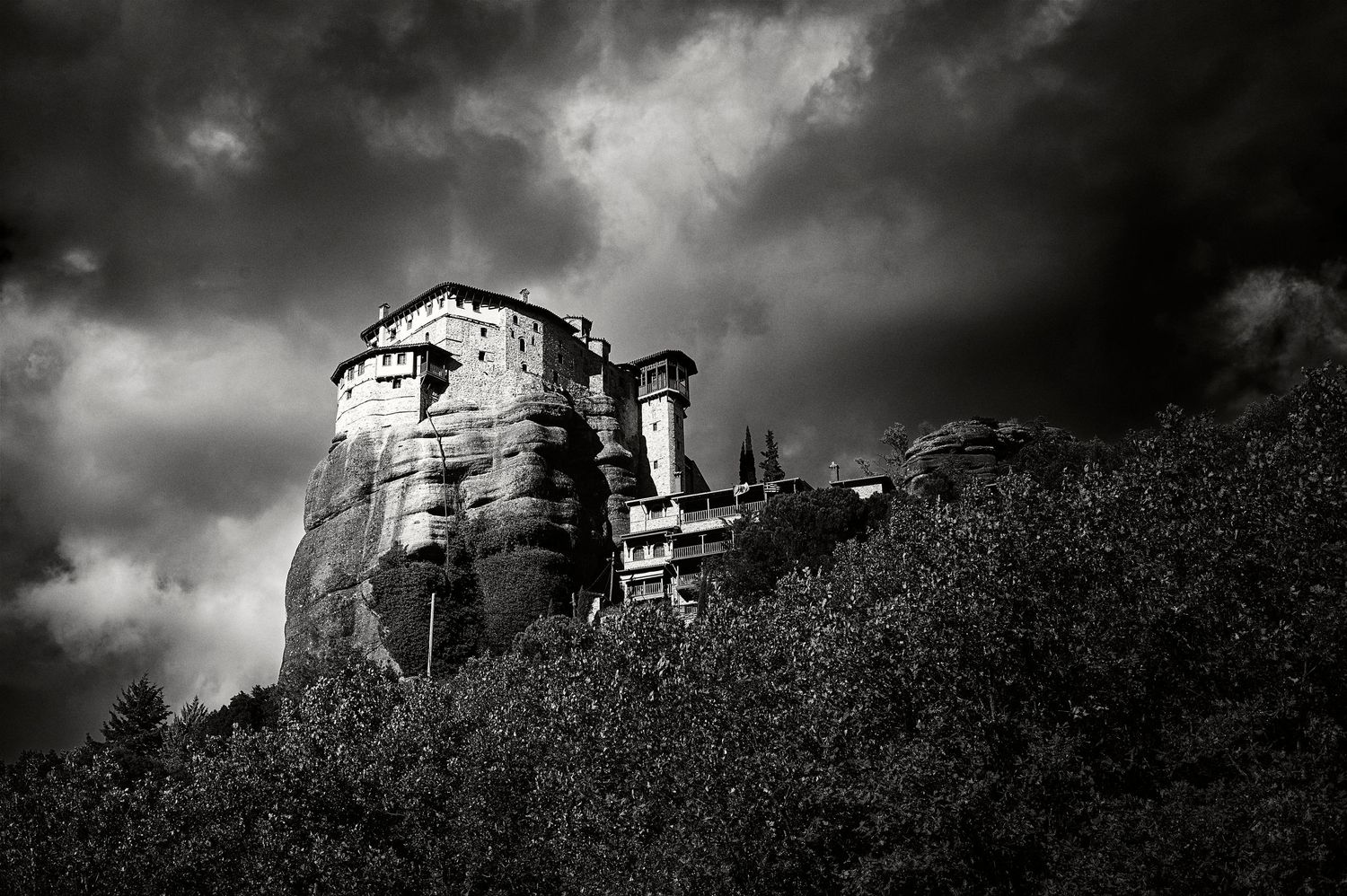 A dramatic black and white photo series shows an abandoned stone building on a hilltop against dark stormy skies.