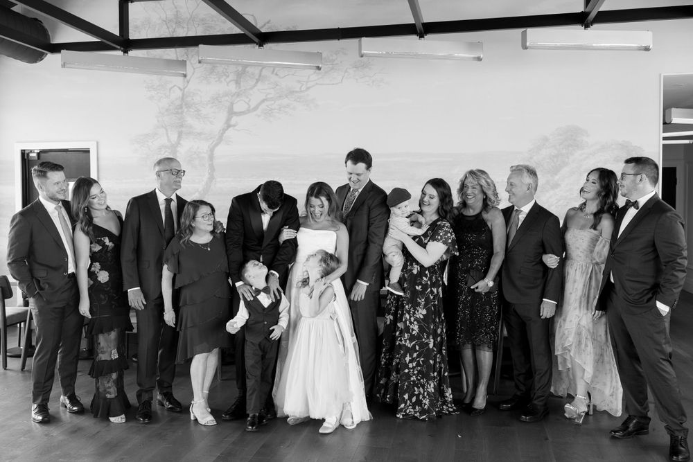 Wedding party group photo with adults and children in formal wear in black and white.