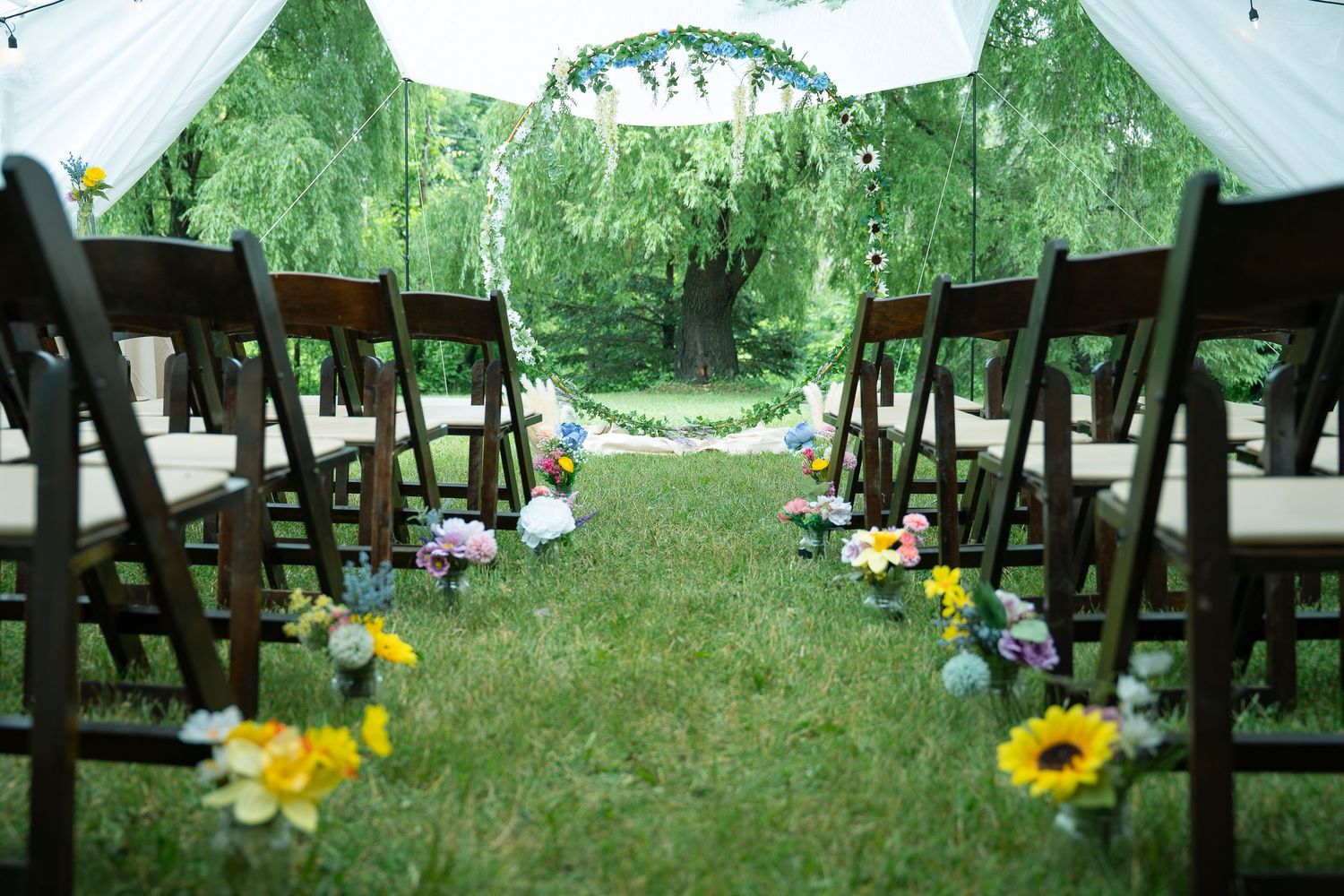 Cette photographie capture une cérémonie de mariage en plein air, au cœur d’un jardin verdoyant. La lumière naturelle, douce et diffuse.
