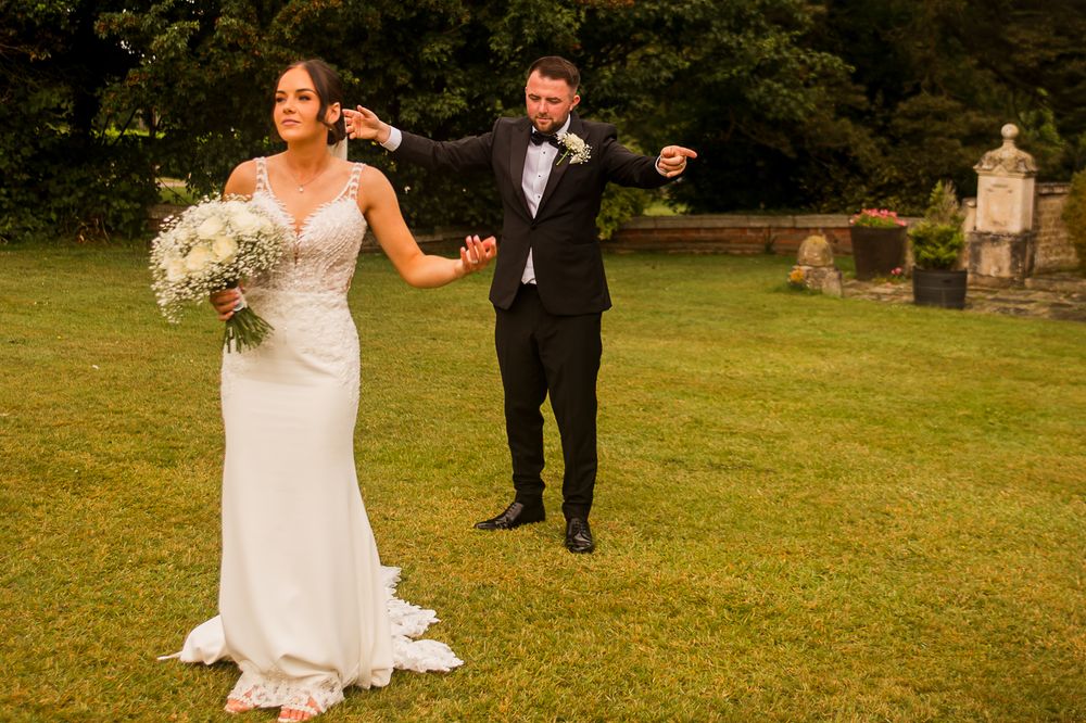 Bride and groom taking outdoor wedding photos in a scenic garden setting.