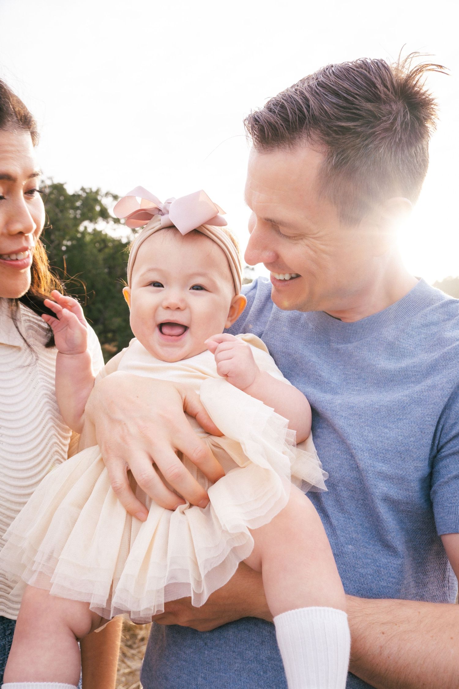 A series of candid family photos showing joyful moments with a baby in a white dress outdoors at sunset.