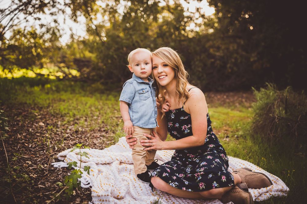 A family sits together on a blanket in a sunlit meadow during a warm summer evening photo session.