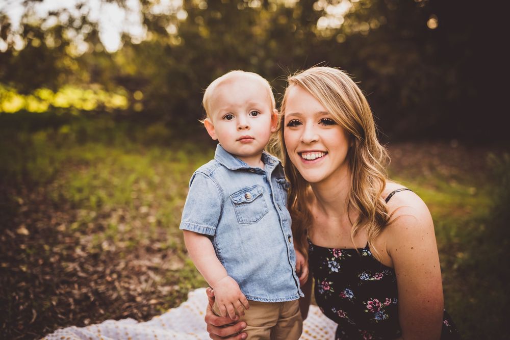 Parent and toddler share joyful moments together during golden hour outdoor photo session.
