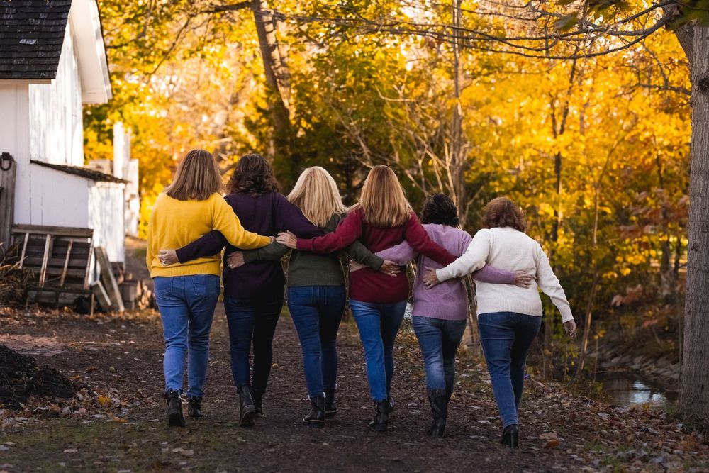 Six women interlocking arms, walking and laughing.
