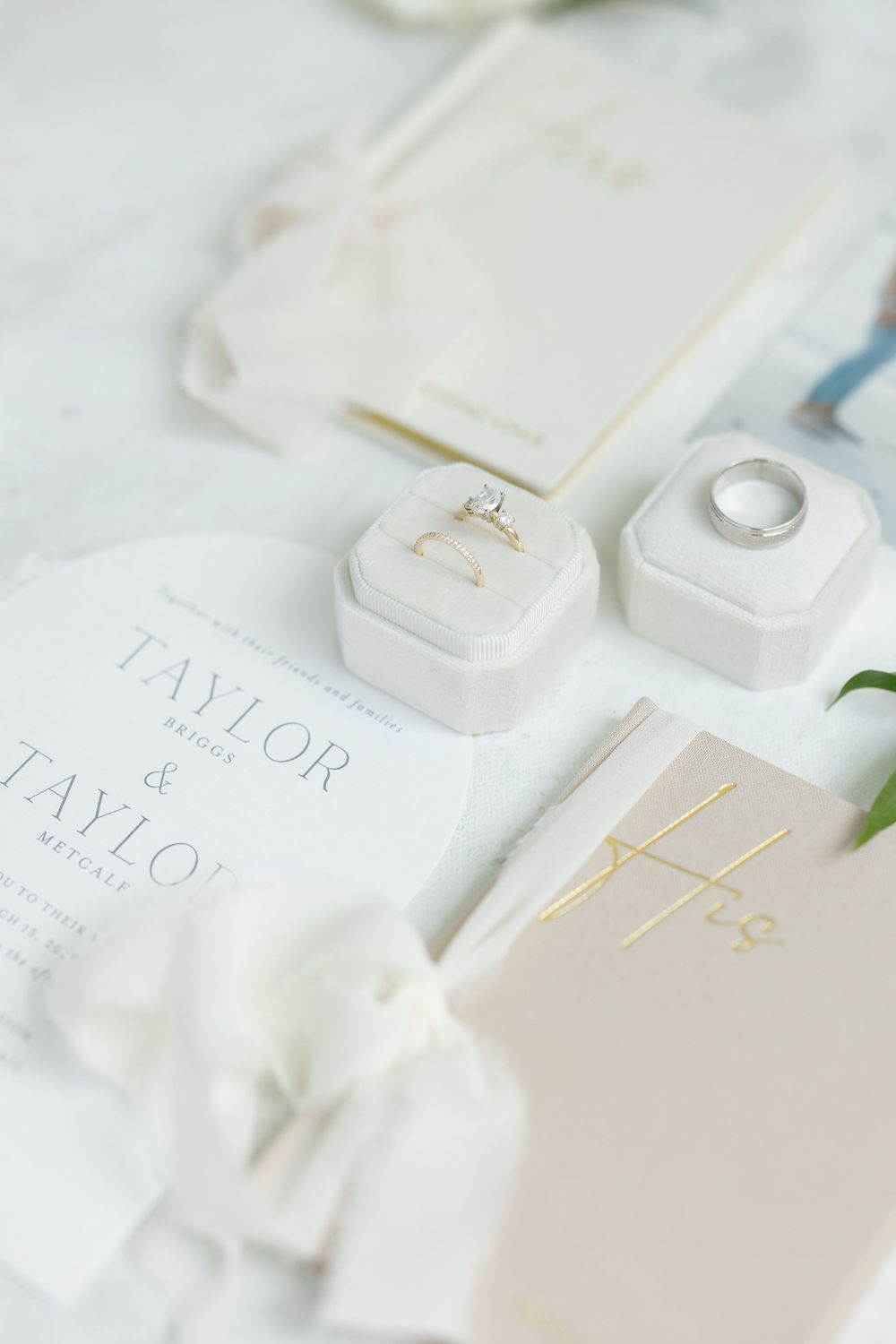 Elegant white wedding stationery and invitations arranged on light background.