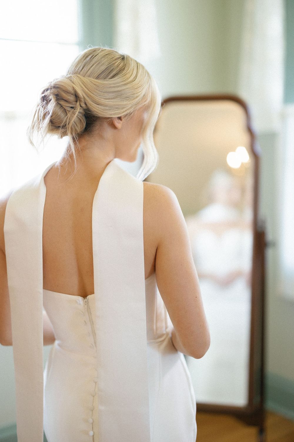 A series of photos showing the back details of an elegant white wedding dress with button closures.