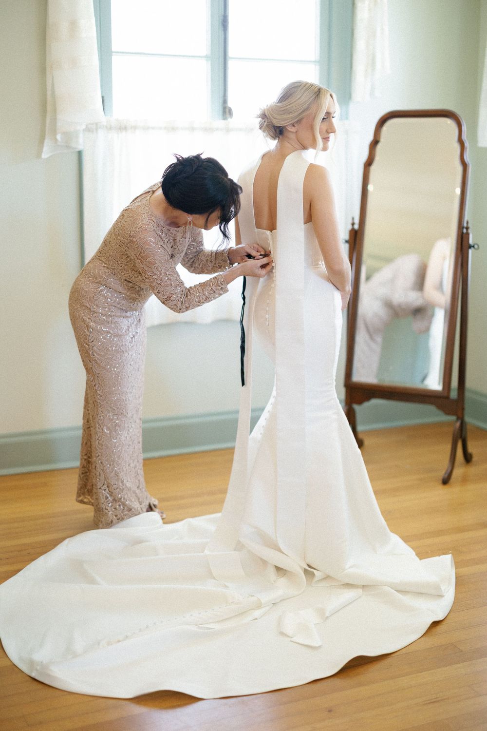 A series of photos showing final wedding dress adjustments and train arrangement in a sunlit room.