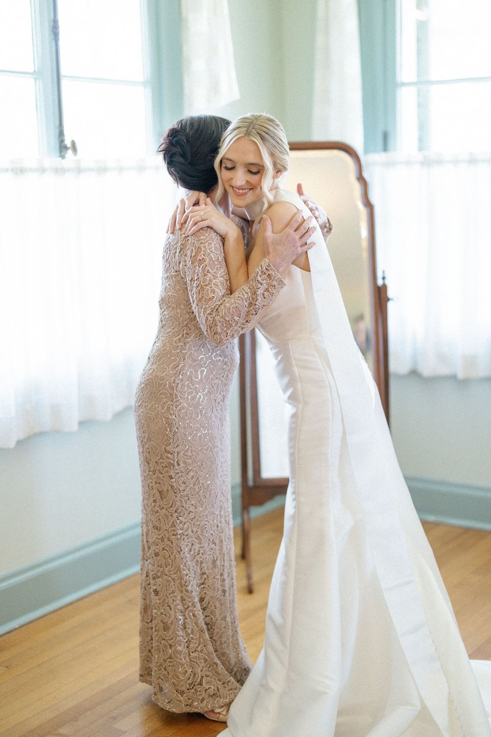 Two people in formal attire share an emotional moment in a sunlit room.