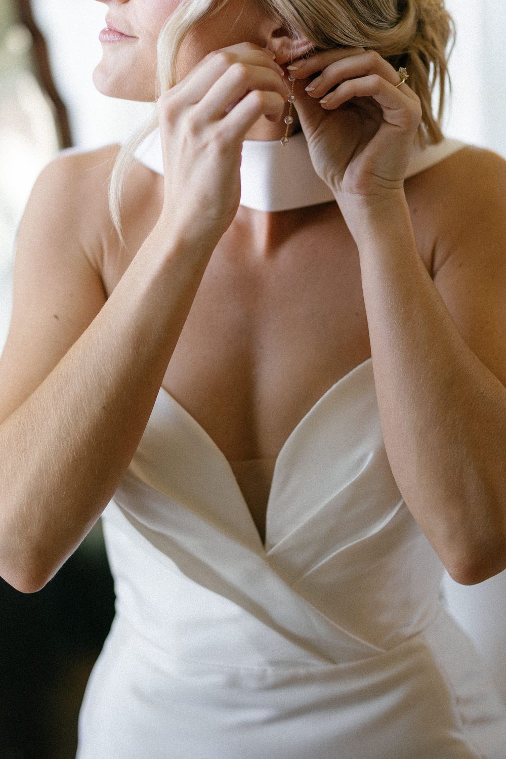 Close-up shots of a bride adjusting her necklace while wearing a white strapless wedding gown.