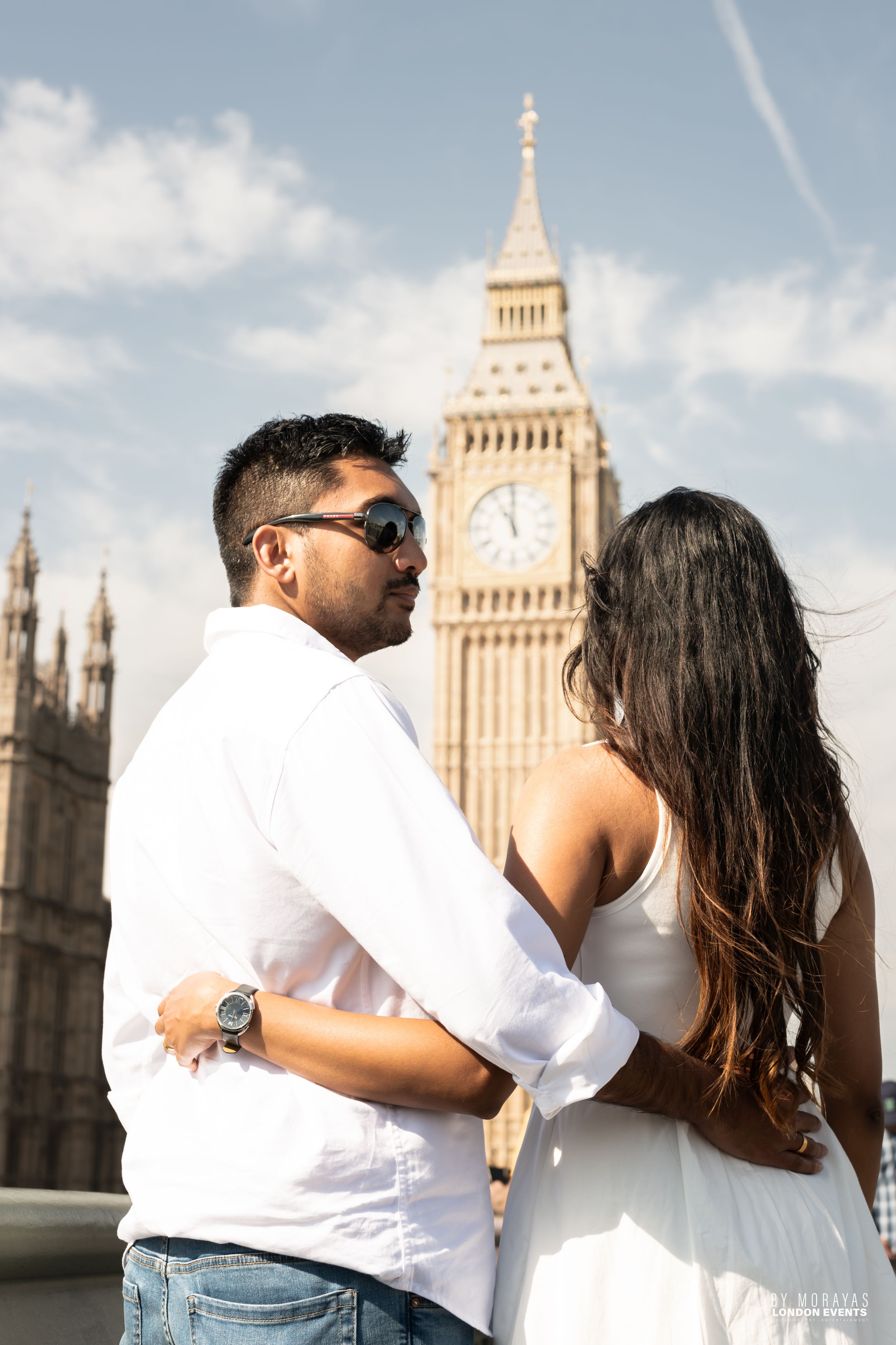 A romantic couple poses in front of Big Ben and Westminster in London wearing white and black outfits.