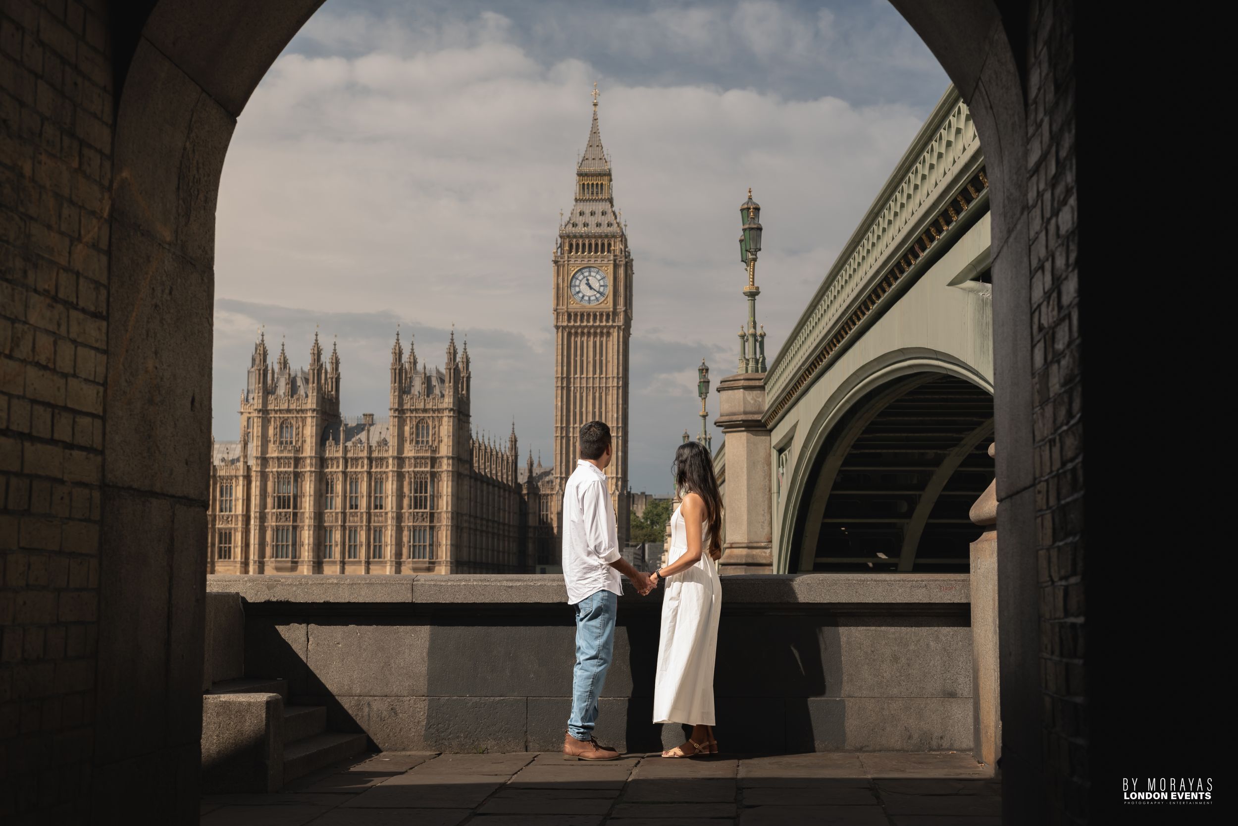 Silhouetted figures stand beneath an archway with Big Ben visible in the background.