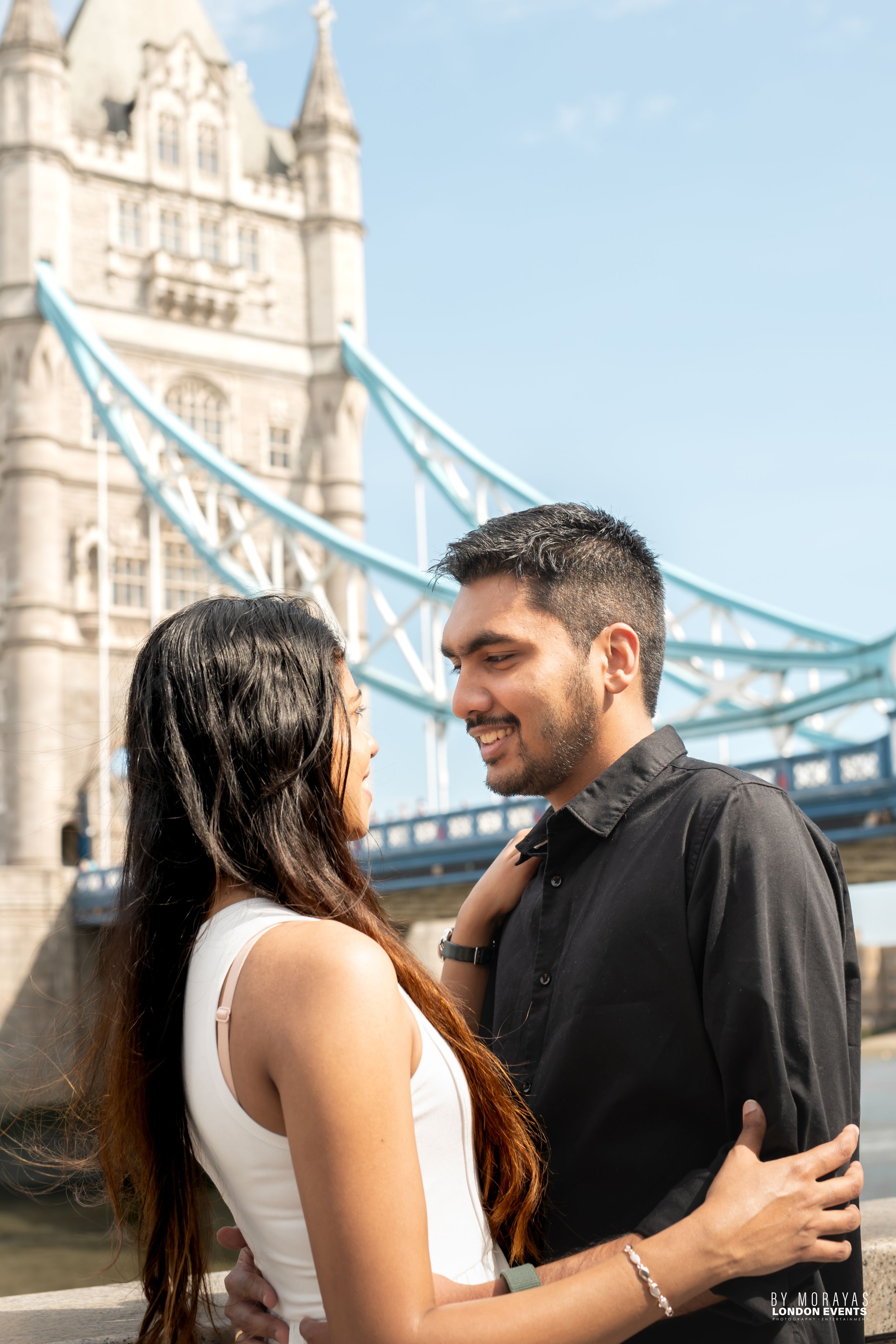 A couple shares a romantic moment in front of London's iconic Tower Bridge.