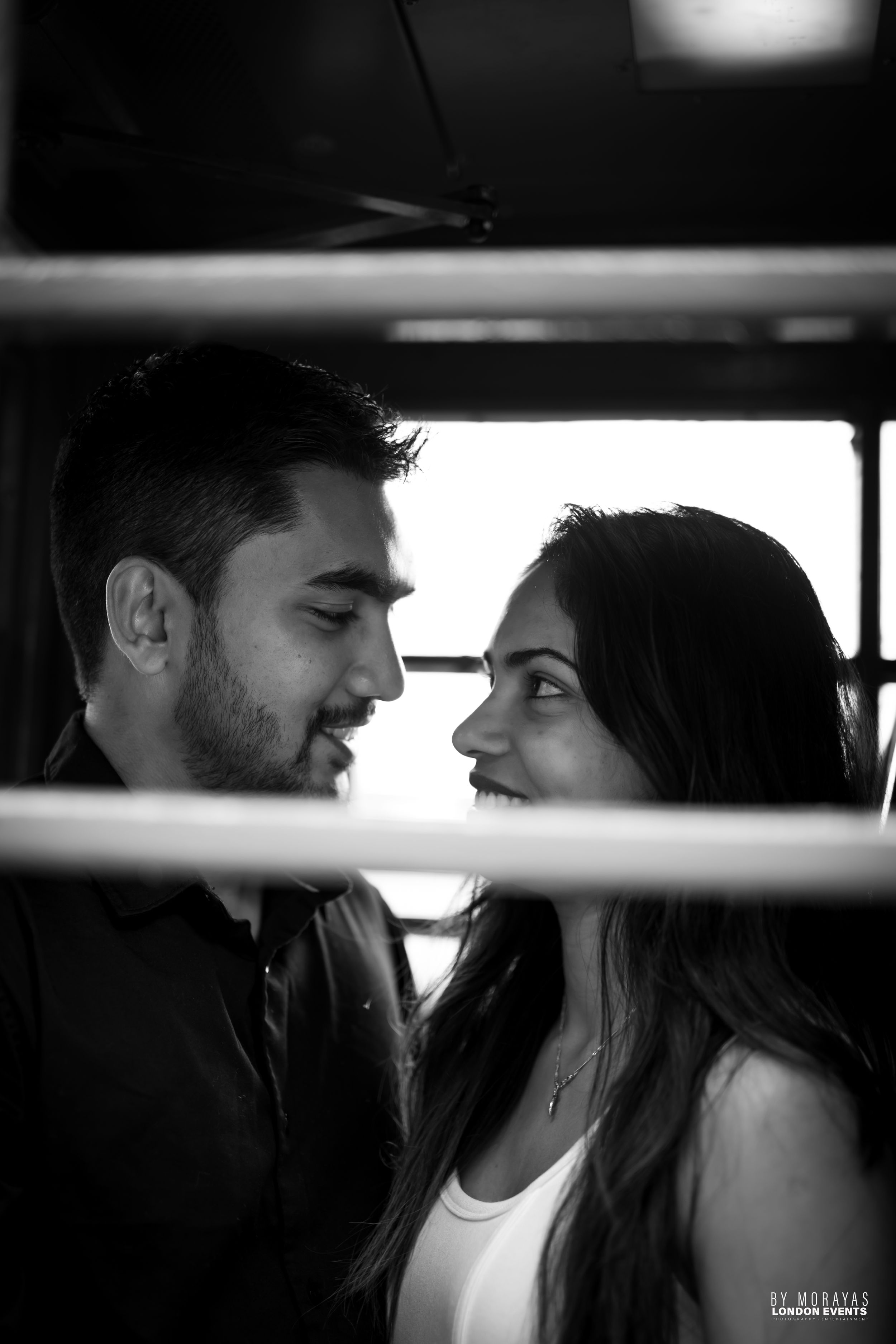 An artistic black and white photo captures an intimate couple's moment through window blinds.